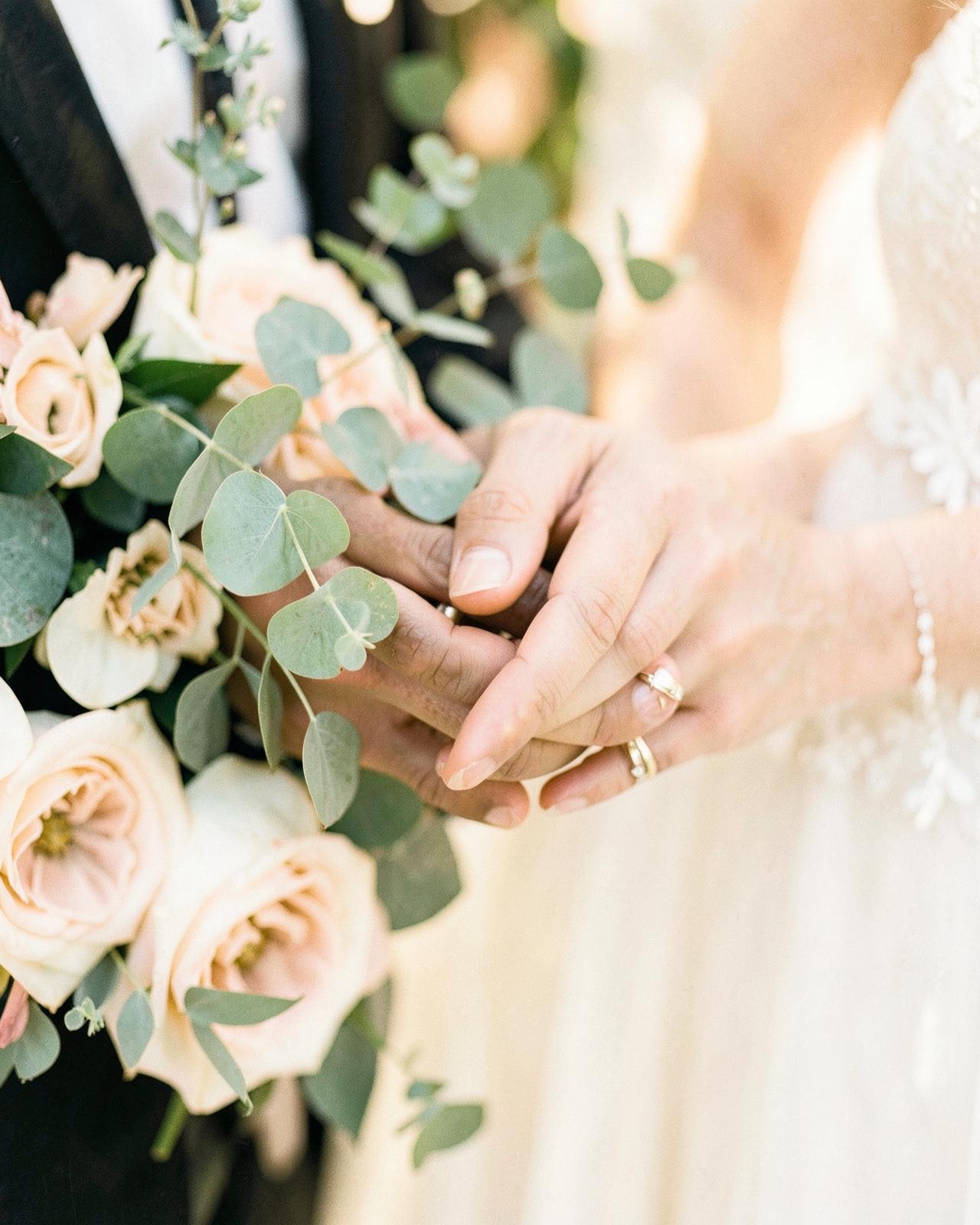 Hands of the couple with a bouquet of blush roses
